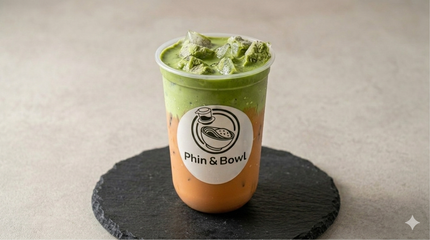 Green smoothie in a clear cup on a black coaster, labeled with a café logo.