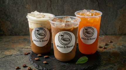 Three iced drinks in clear cups on a table, with whipped cream on two and orange tea on the right.