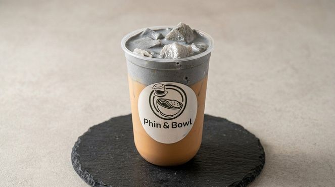 A small iced drink in a clear cup with a logo, sitting on a black coaster.