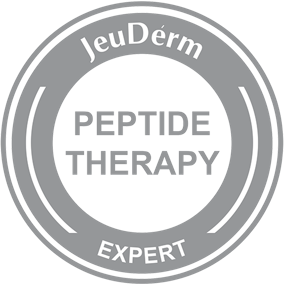JeuDerm “Peptide Therapy Expert” apaļš pelēks logotips ar baltu centru un pelēku tekstu