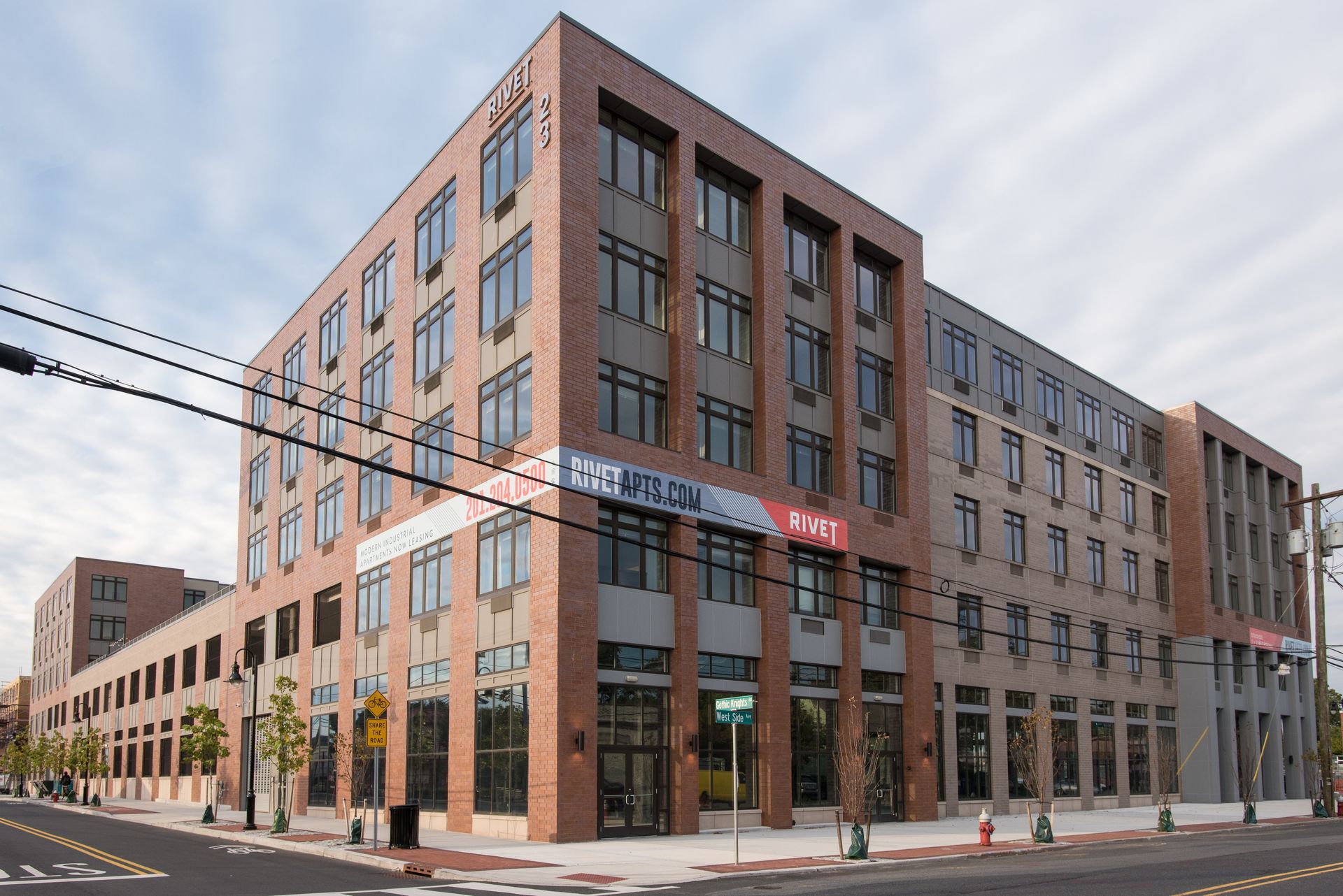 A large brick building with a lot of windows is on the corner of a street.