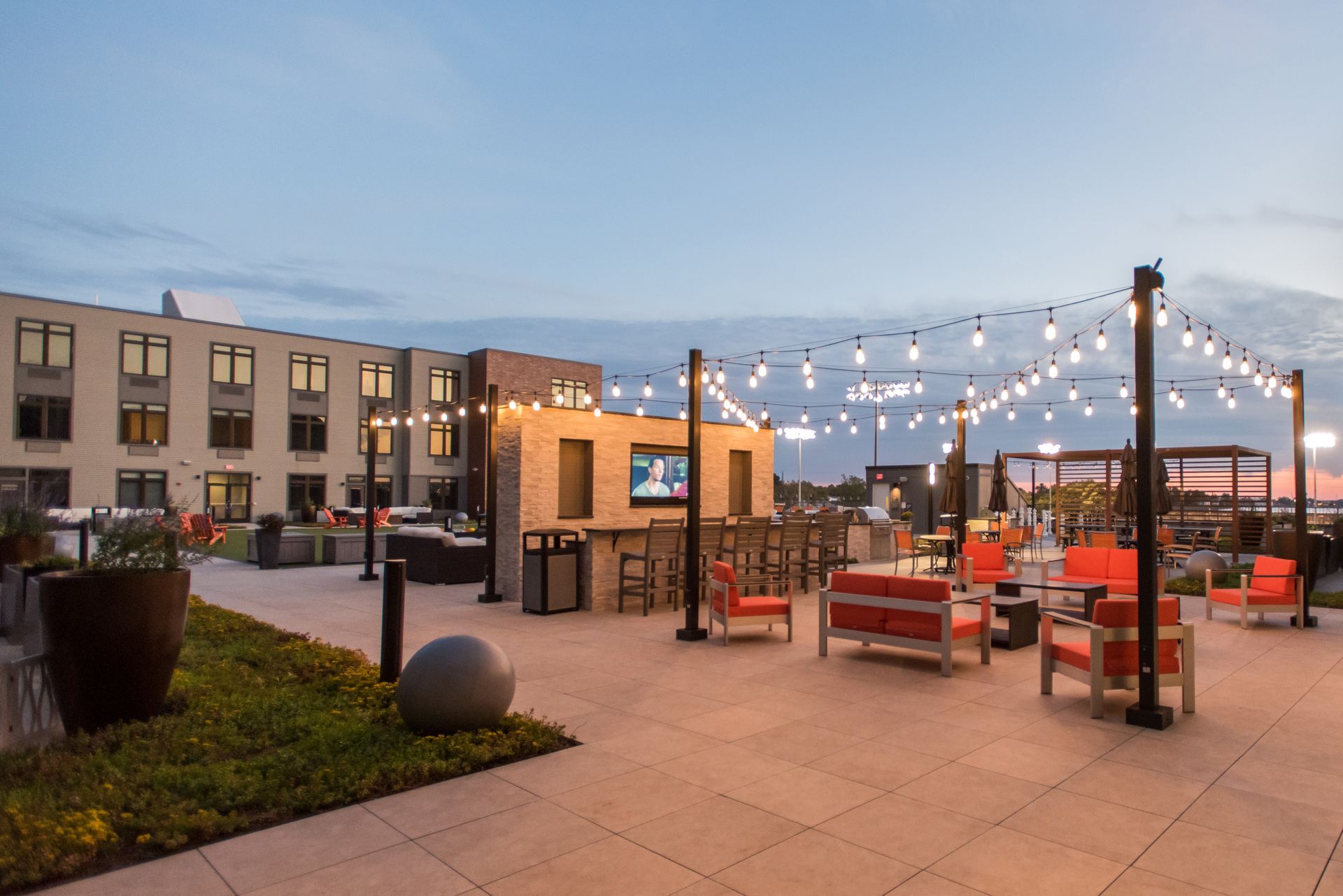 A patio with chairs , tables , umbrellas and a television.