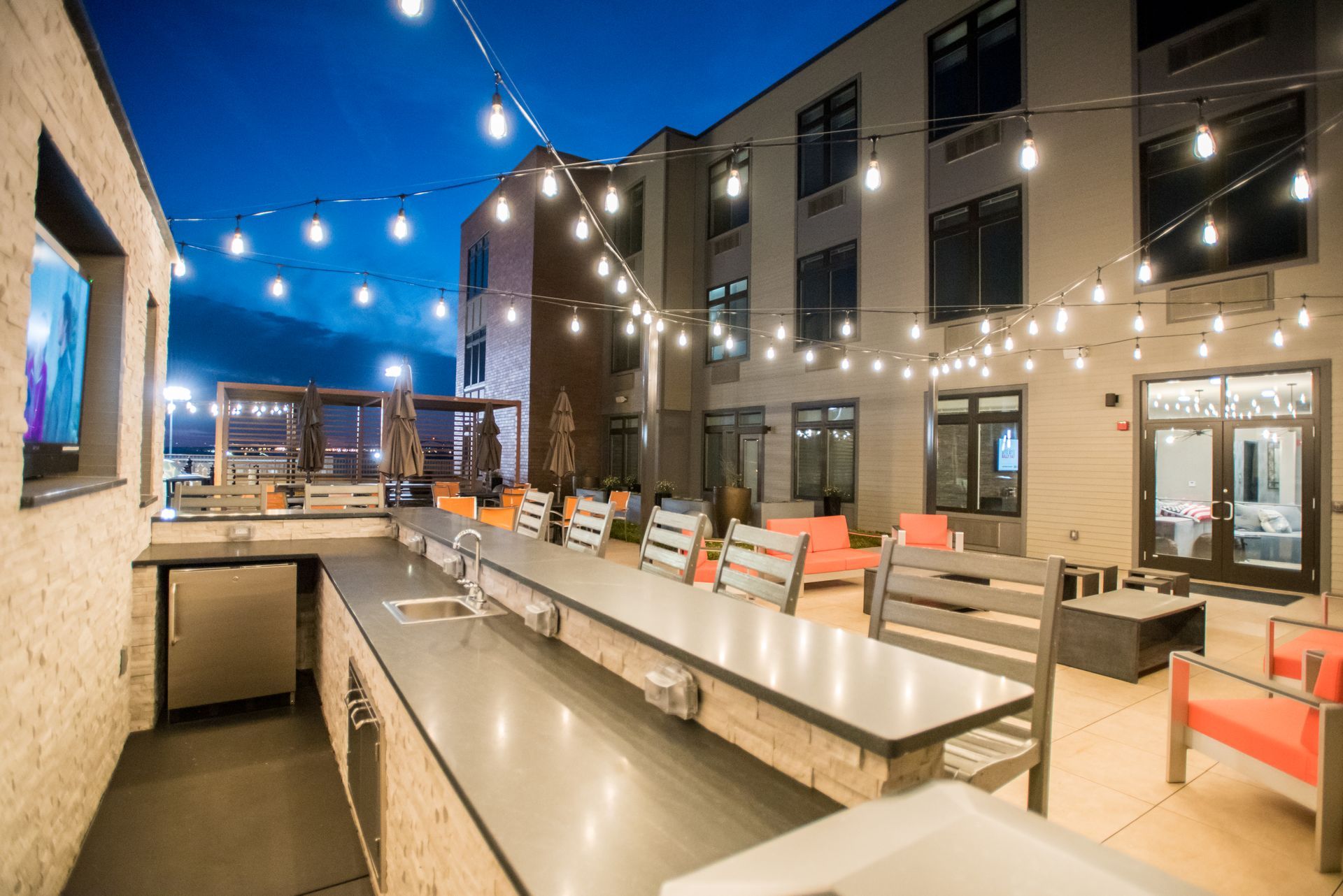 A patio area with a long table and chairs in front of a building.