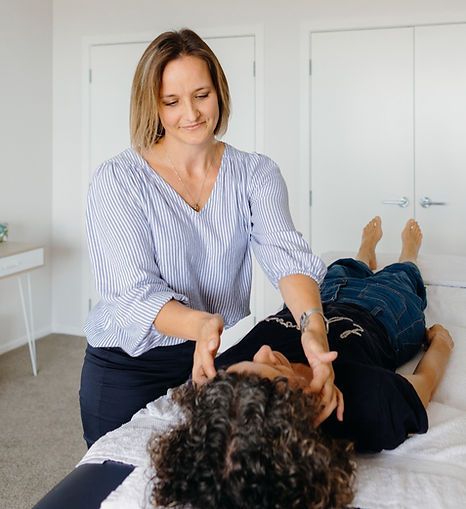 Massage therapist working on a client lying face down on a treatment table in a bright room