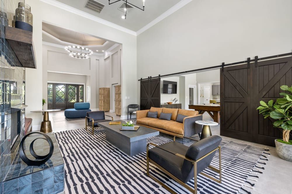 a living room with a couch, chairs, coffee table, and sliding barn doors at Marquis Carmel Commons in Charlotte, NC.