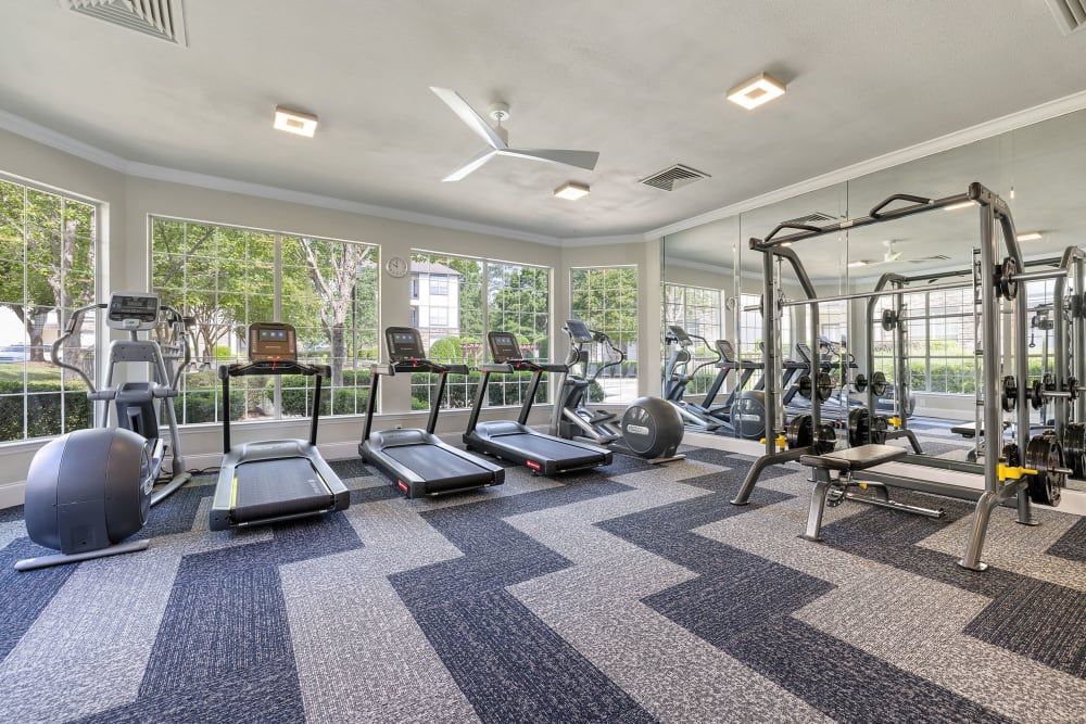 a large gym with treadmills, exercise bikes, and a ceiling fan at Marquis Carmel Commons in Charlotte, NC.
