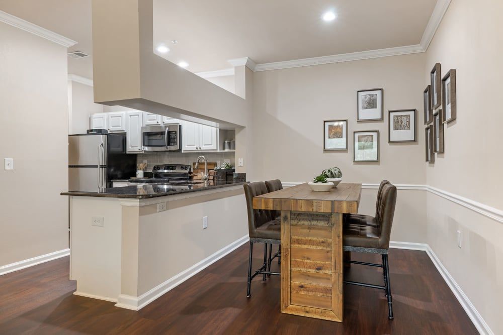 a kitchen and dining room in a house with a wooden table and chairs at Marquis Carmel Commons in Charlotte, NC.