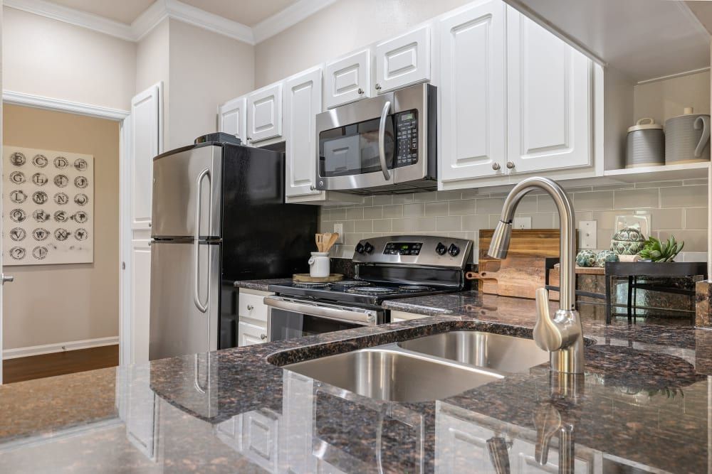 a kitchen with stainless steel appliances and granite counter tops at Marquis Carmel Commons in Charlotte, NC.