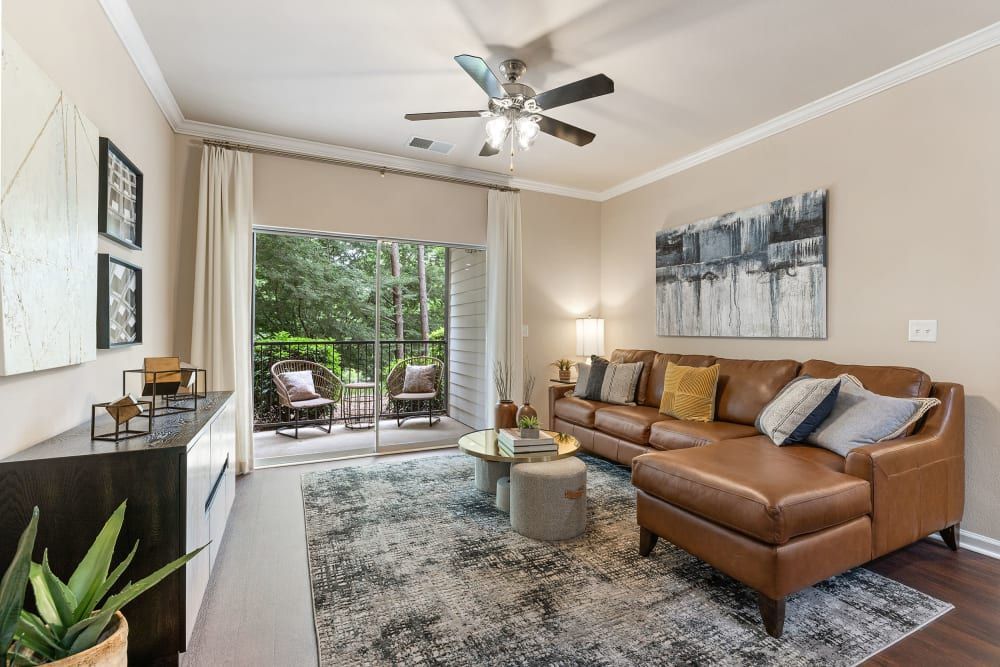 a living room with a couch, coffee table, and ceiling fan at Marquis Carmel Commons in Charlotte, NC.