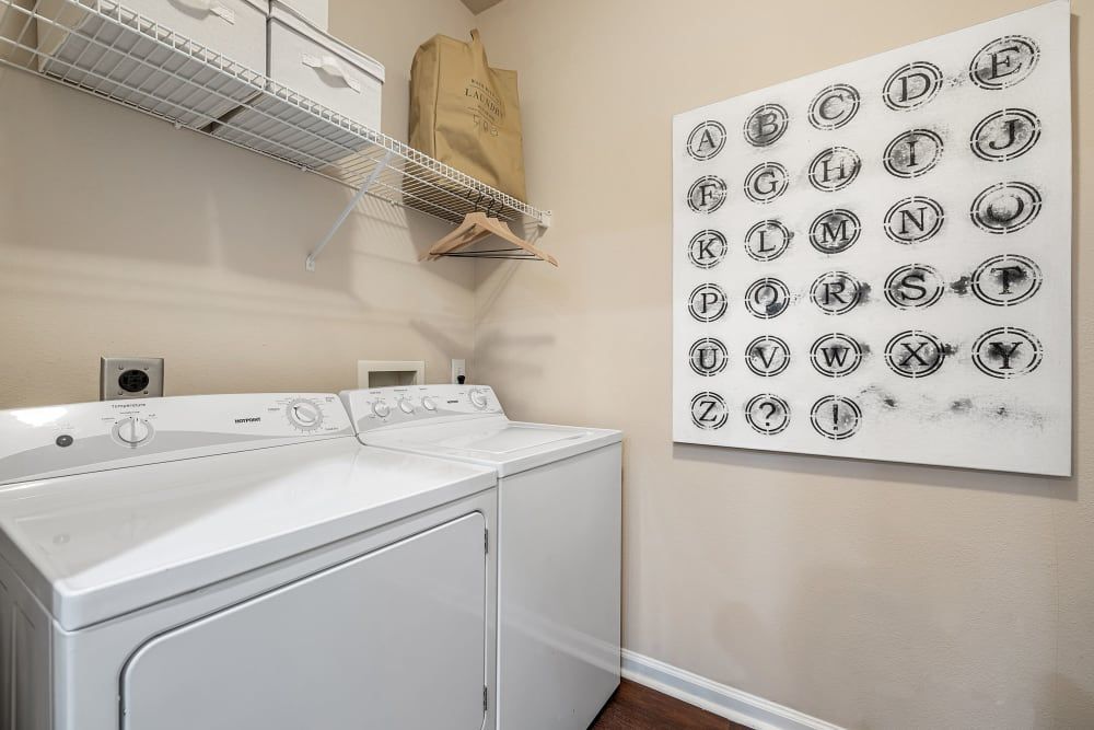 a laundry room with a washer and dryer and a painting on the wall at Marquis  Carmel Commons in Charlotte, NC.
