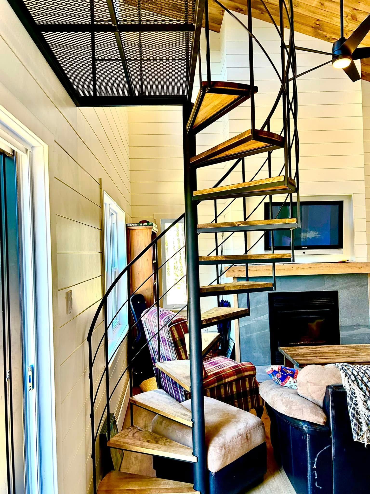 Escalier en colimaçon dans une pièce étroite avec une chaise, une table et une cheminée près d'une porte bleue