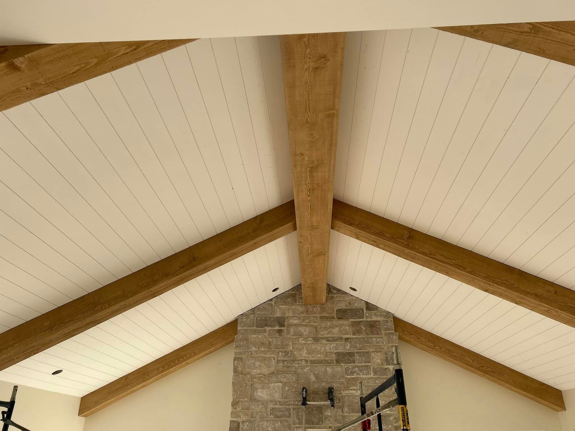 Plafond voûté à poutres apparentes avec lambris blancs et cheminée en pierre en dessous