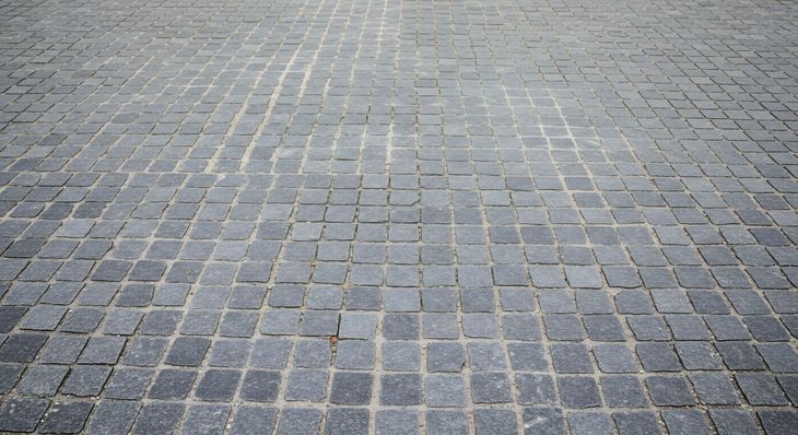 A close-up of dark grey, rectangular paving stones arranged in a grid pattern.