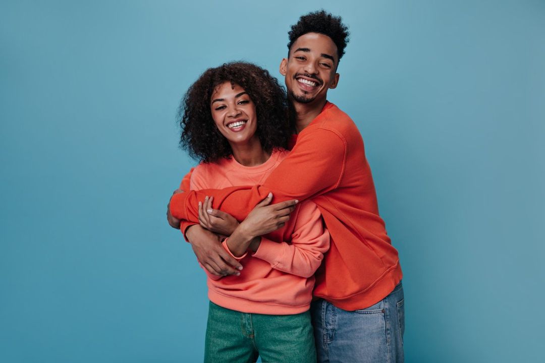 A man and a woman are hugging each other on a blue background.