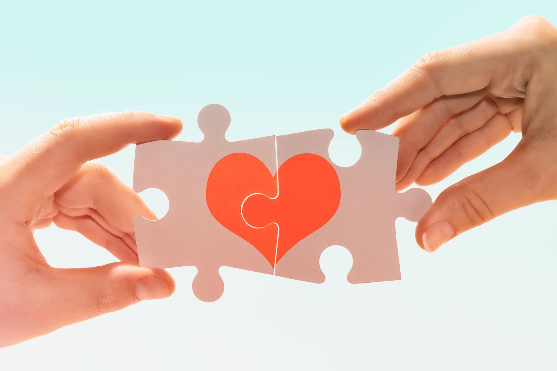 due persone che tengono in mano due caselle di puzzle con disegnato sopra un cuore