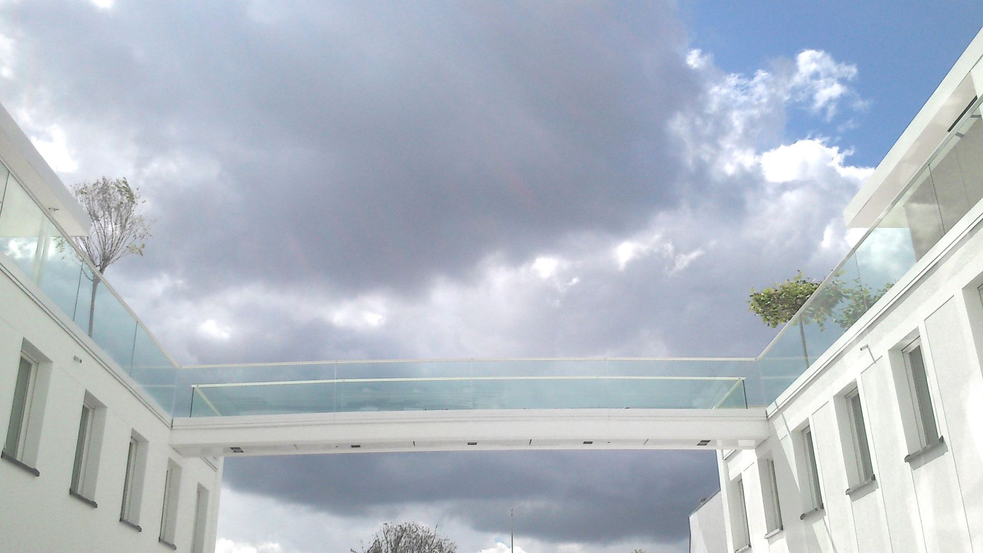 Eine Brücke zwischen zwei Gebäuden mit einem bewölkten Himmel im Hintergrund.