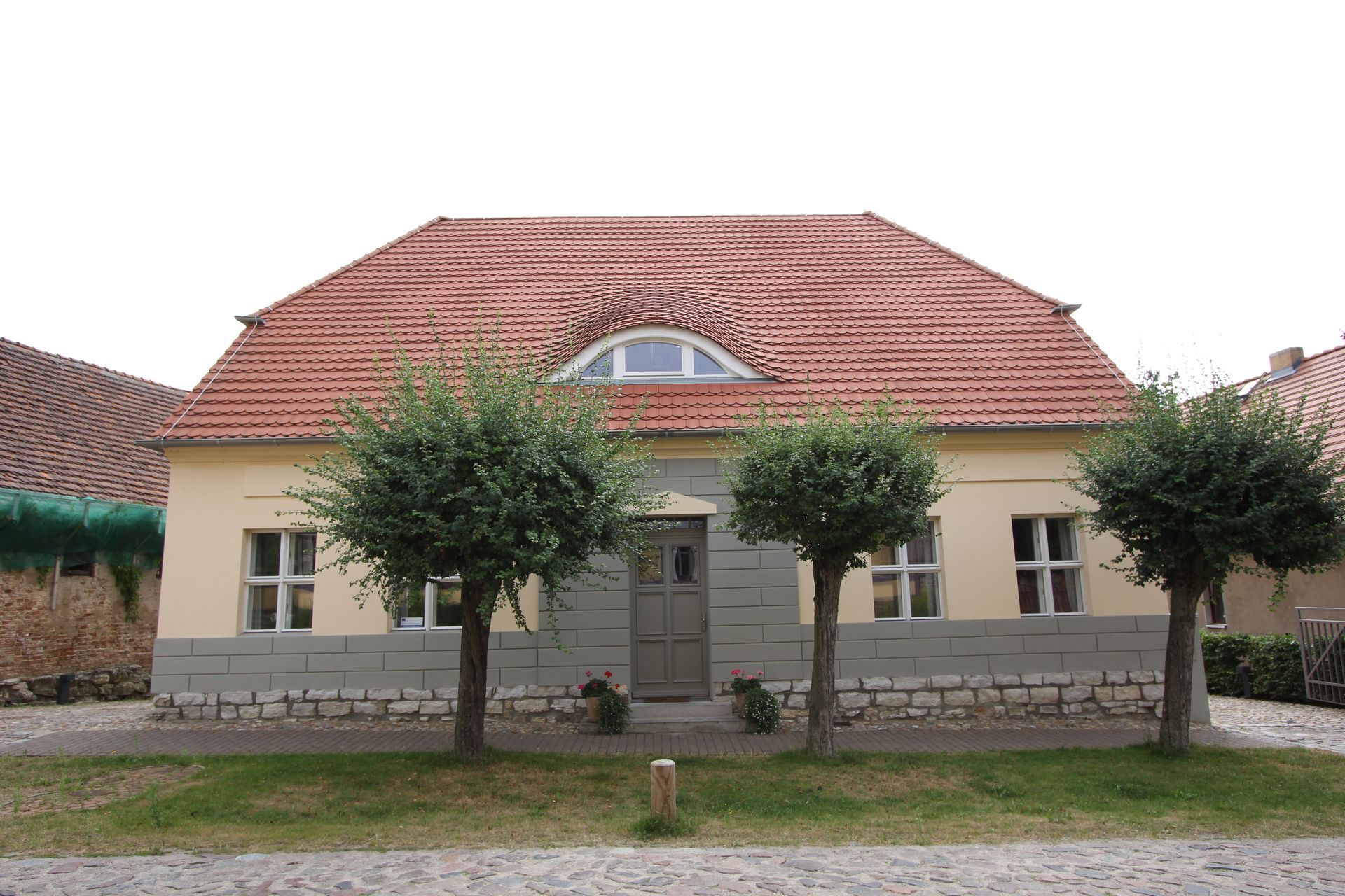 Ein Haus mit einem roten Ziegeldach und Bäumen davor
