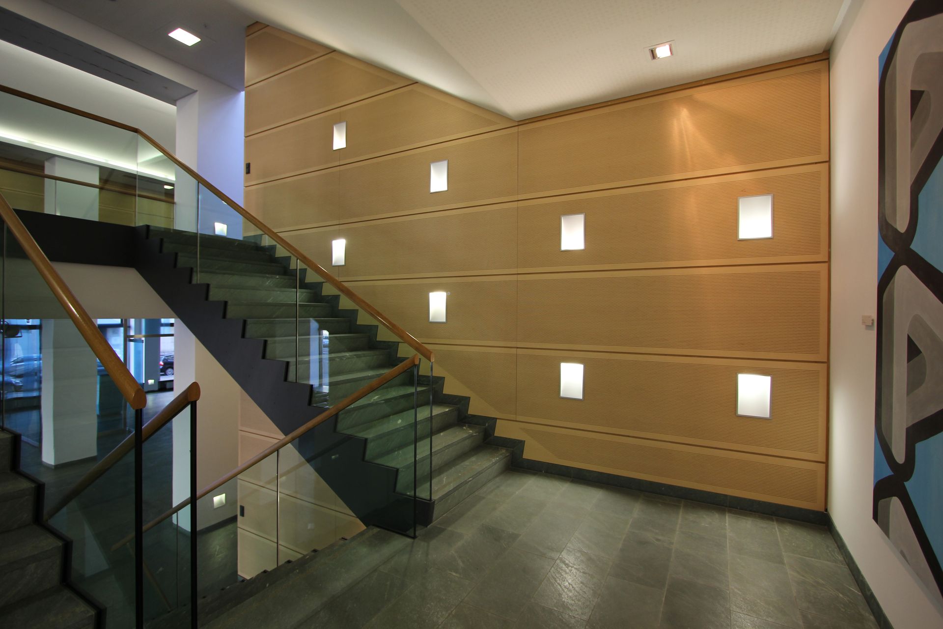 Eine Treppe mit einem Glasgeländer und einer Holzwand