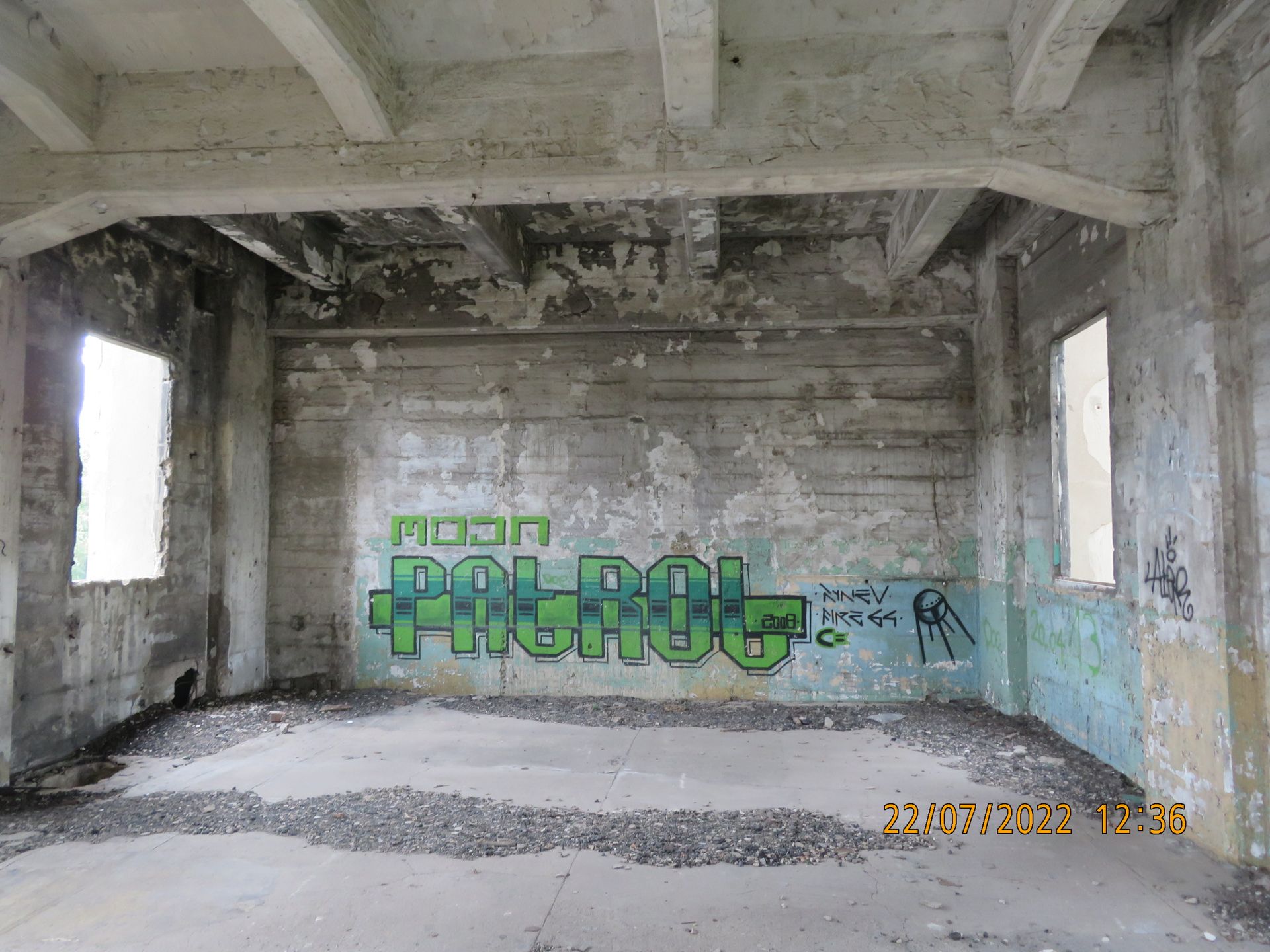 Ein leerer Raum mit Graffiti an der Wand, auf dem „Patrouille“ steht