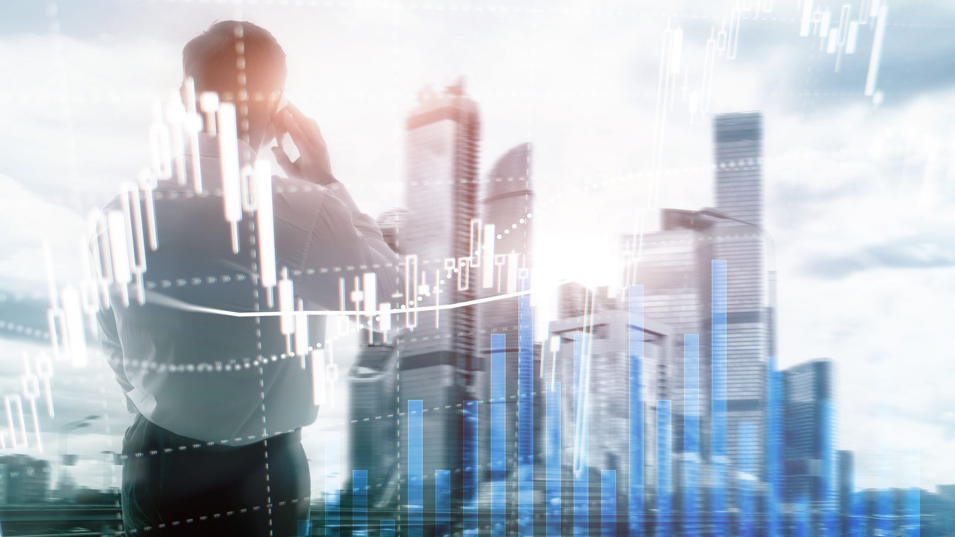 Silhouetted person analyzing city skyline with glowing stock charts and financial graphs overlayed