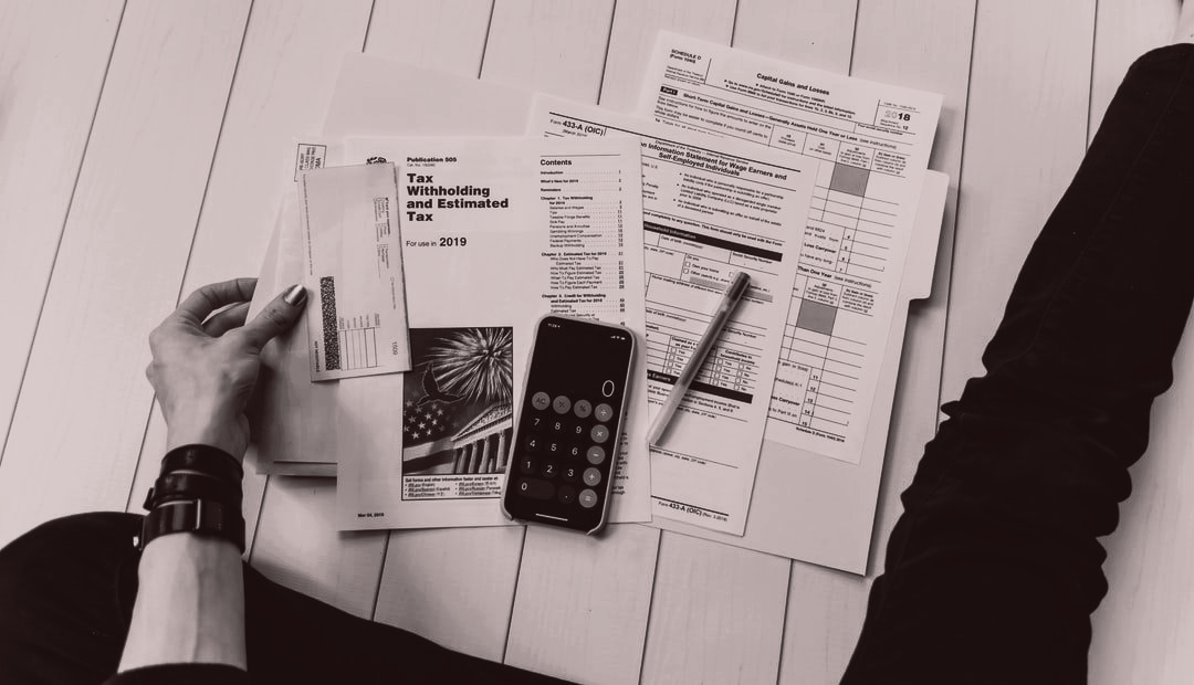 Hands reviewing planner pages with a calculator and pen on a white desk