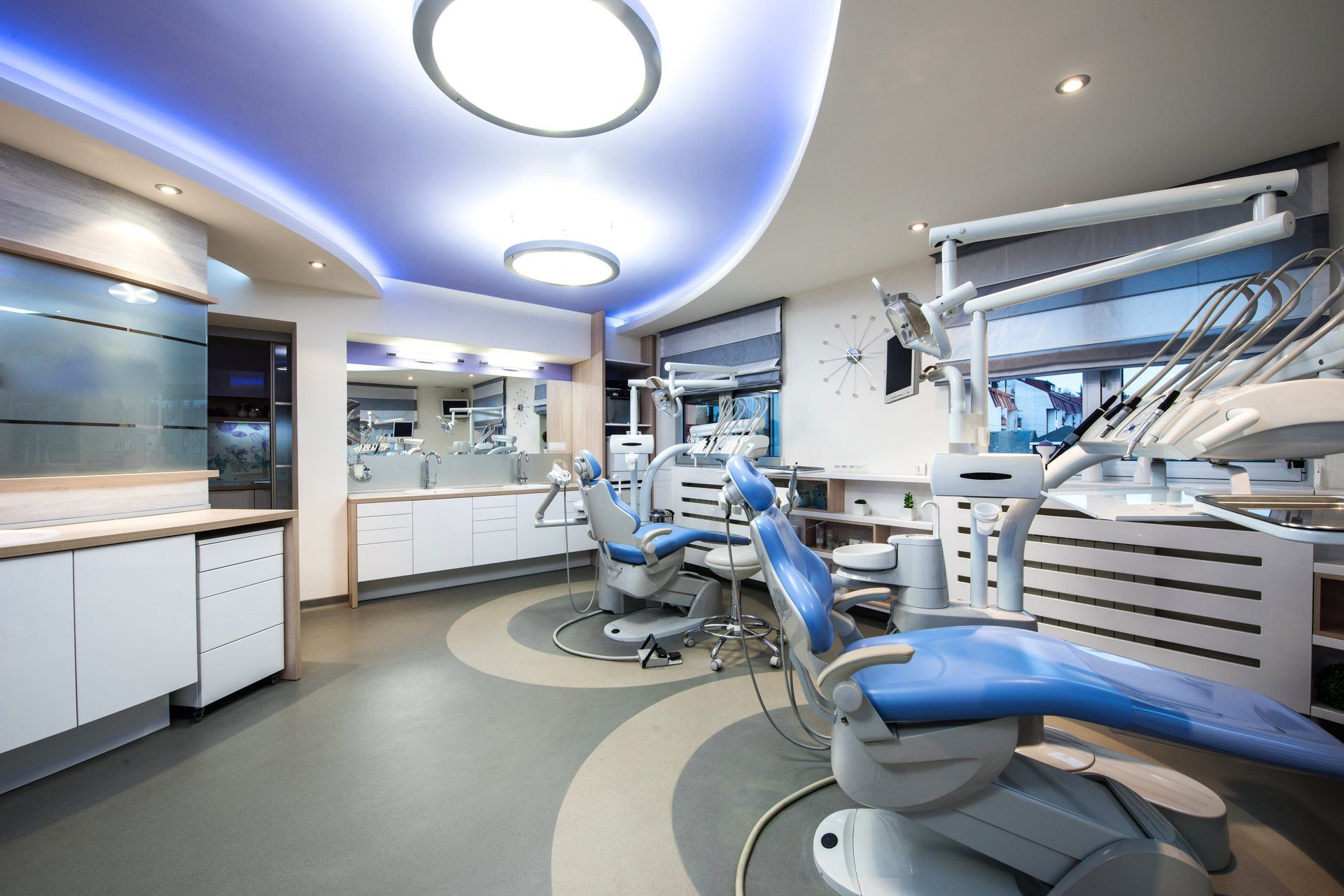 Modern dental office with blue and white chairs, equipment, and lighting.
