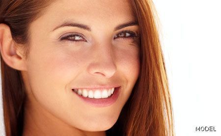 A close up of a woman 's face smiling on a white background.