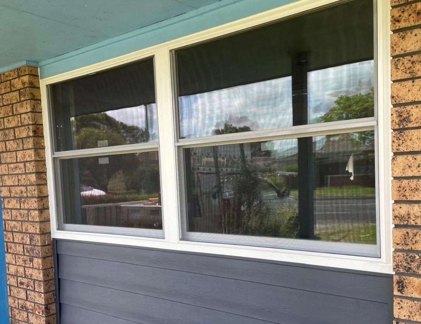 New UPVC double glazed window and composite cladding on a brick and blue painted house exterior.