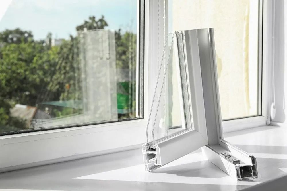 White window frame open to a sunny view, with a small white window vent or fan on the sill.