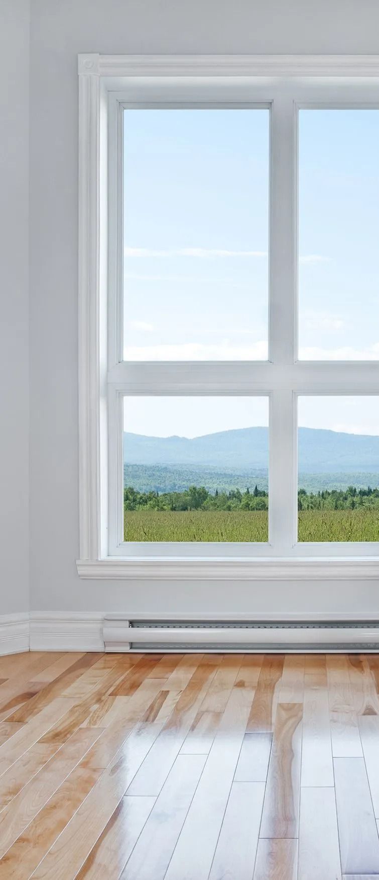 Two white-framed sliding windows on a yellow house. Sheer curtains partially cover the window panes.