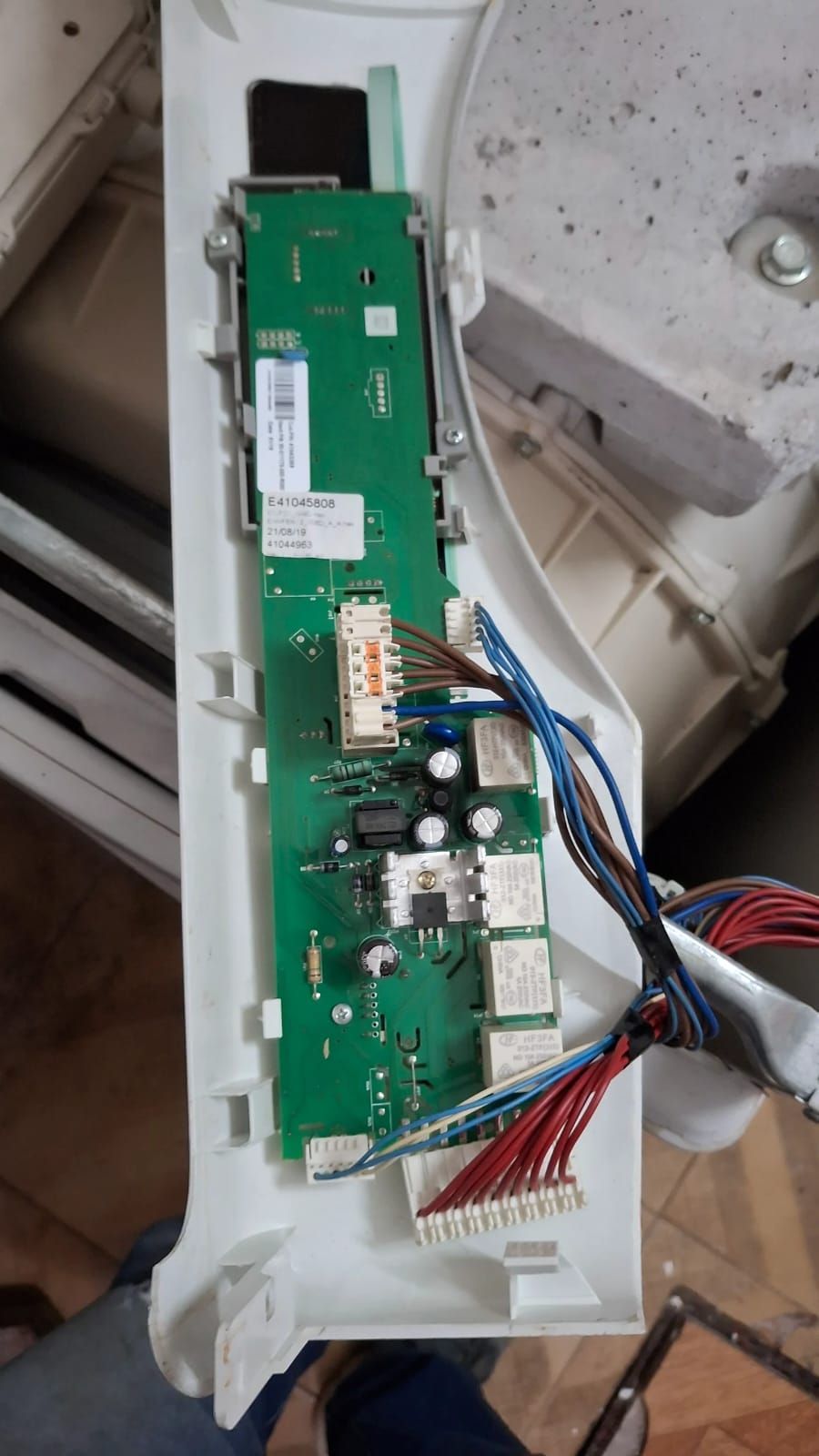 Primer plano de una placa de circuito verde con cables y conectores dentro de una carcasa de plástico blanco.