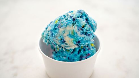 White bowl of blue and cream ice cream on a light background