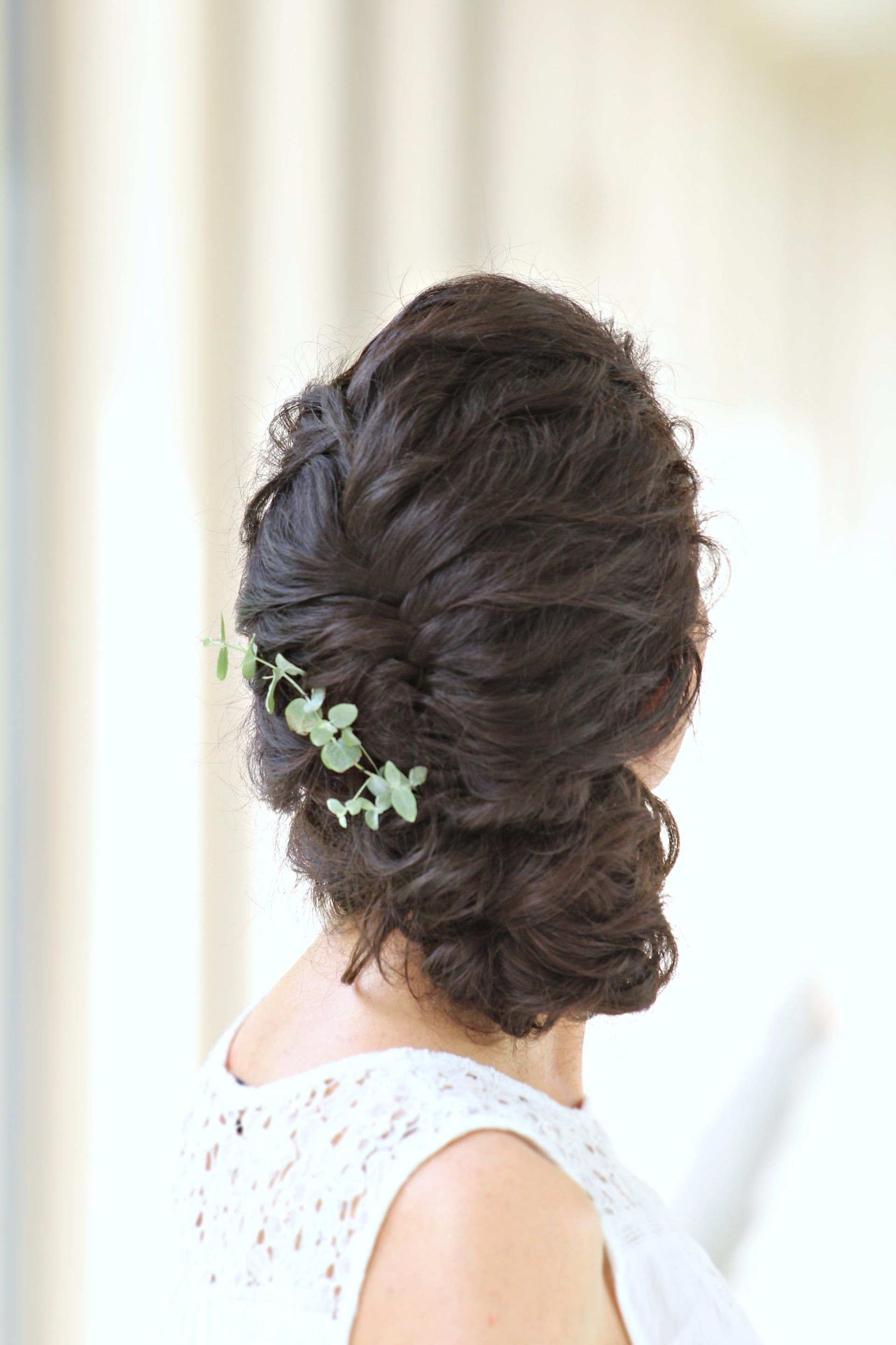 Eine Frau trägt einen Dutt mit Blumen im Haar.