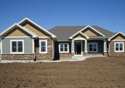 A house with a lot of windows is sitting in the middle of a dirt field