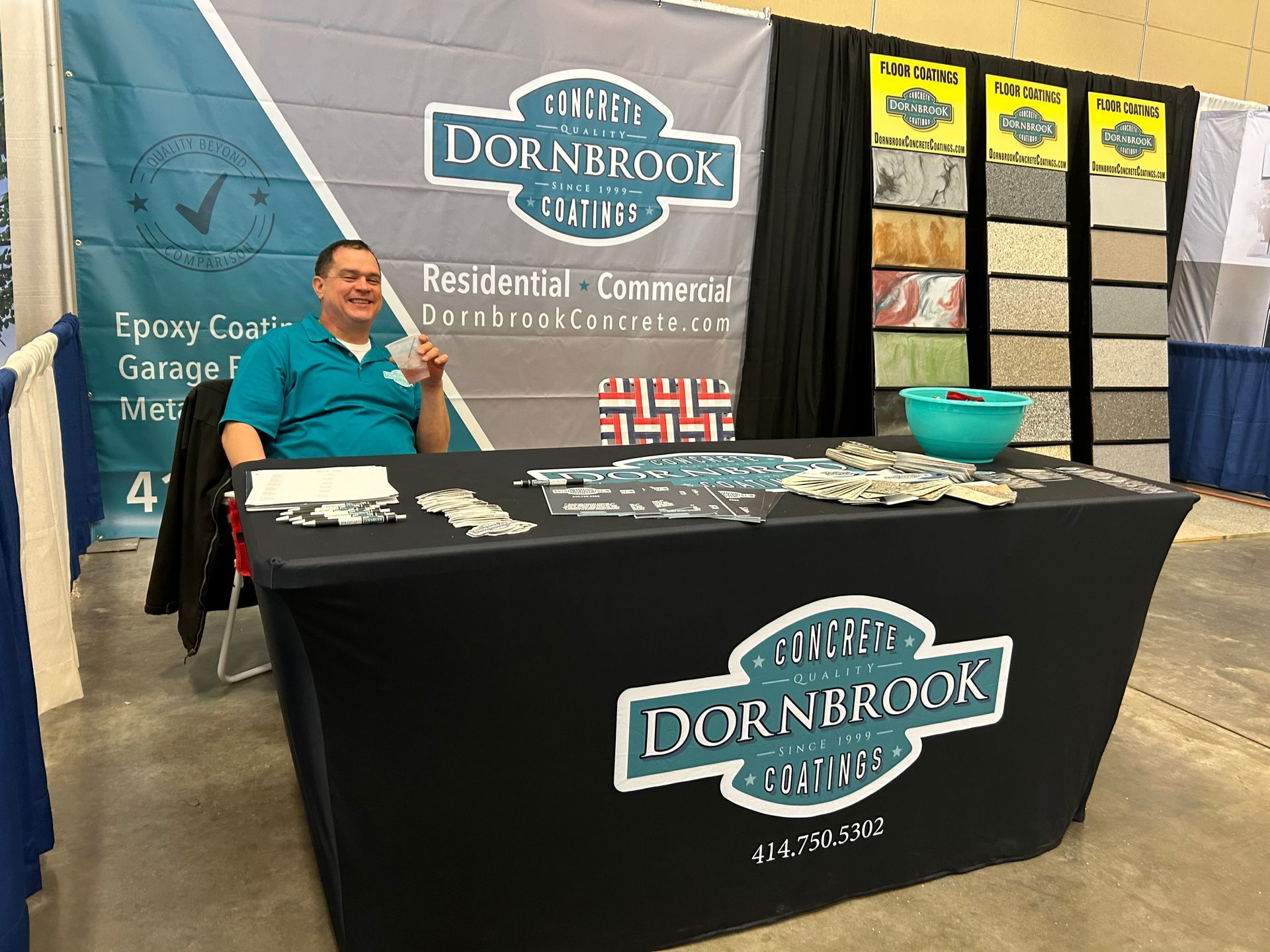 A man is sitting at a table in front of a dornbrook sign.