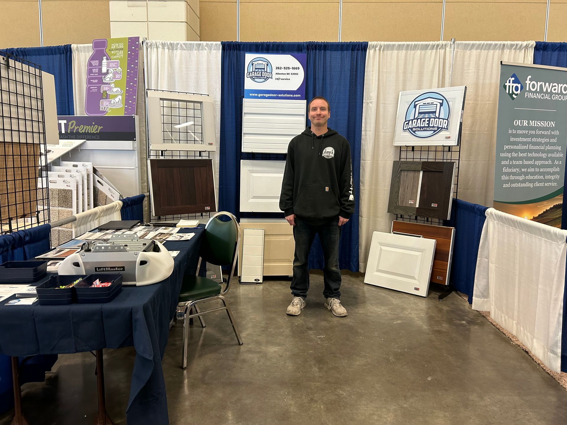 A man is standing in front of a booth at a trade show.