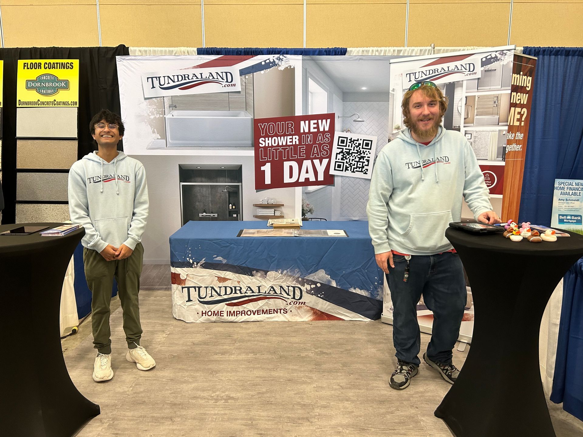 Two men are standing in front of a table with a sign that says 1 day.