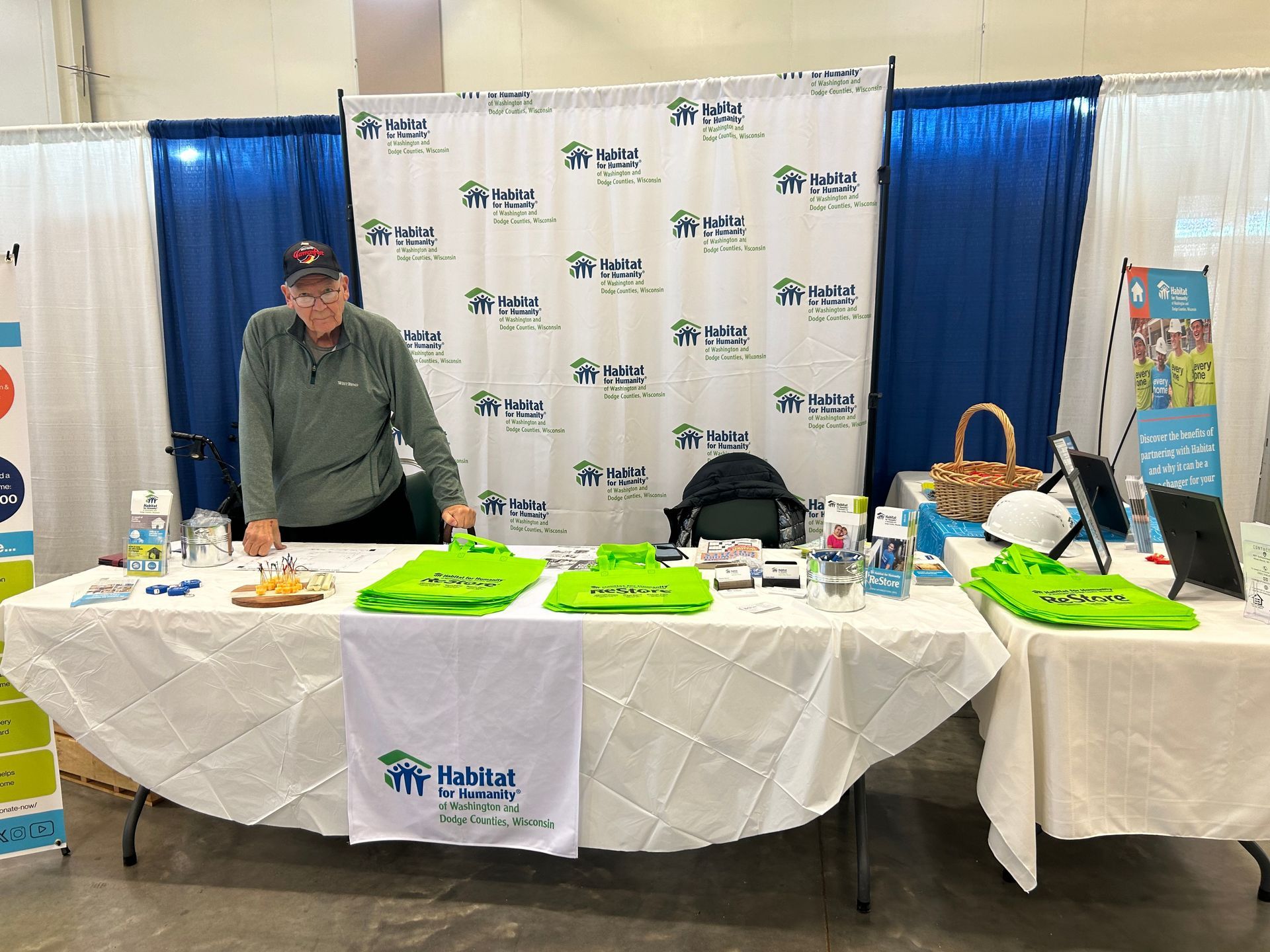 A man is standing in front of a table at a convention.
