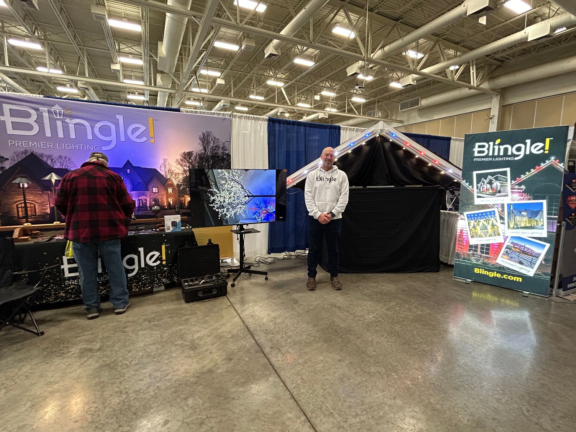 A man is standing in front of a booth at a convention.