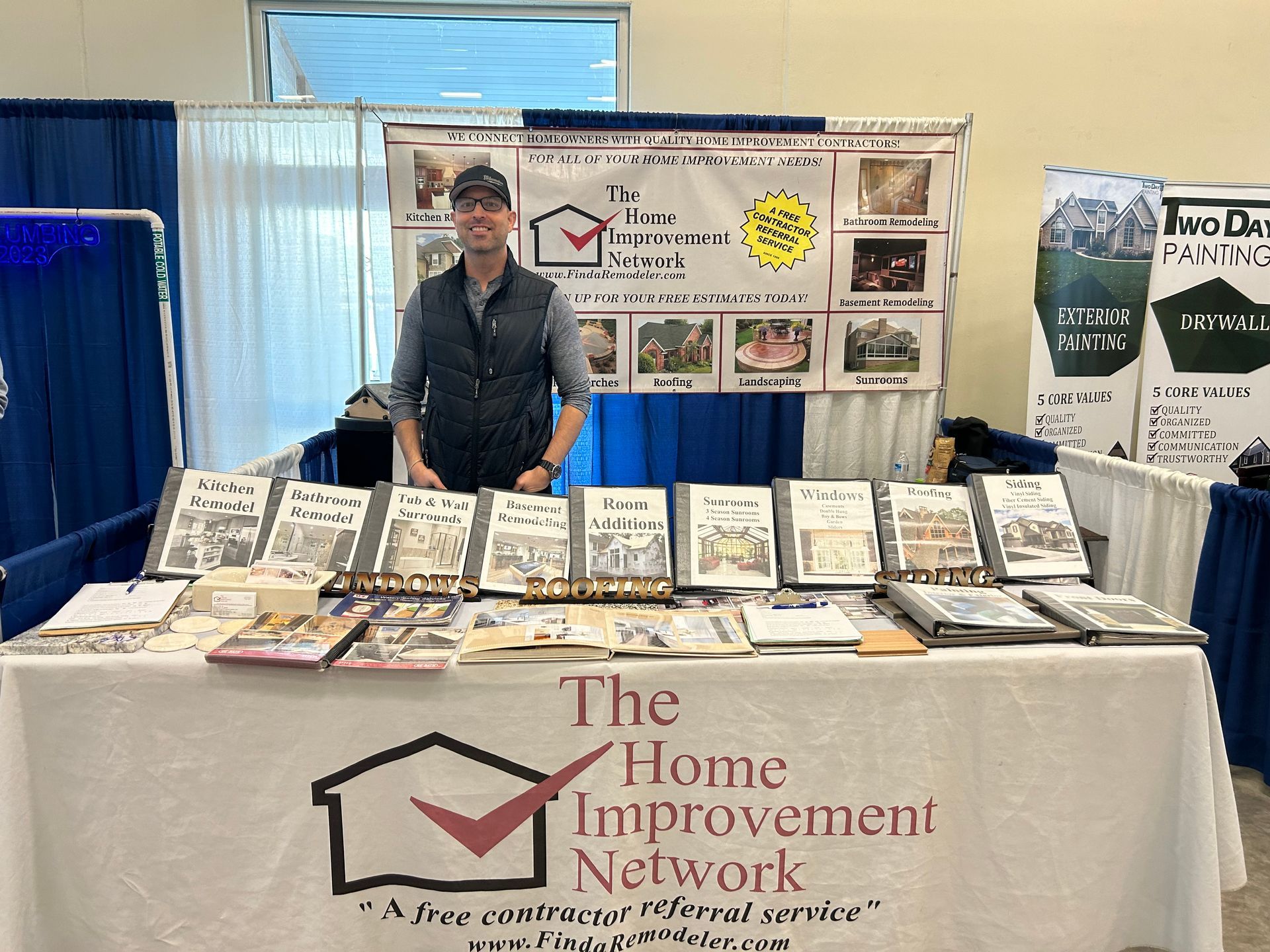 A man is standing in front of a table with a sign that says the home improvement network.