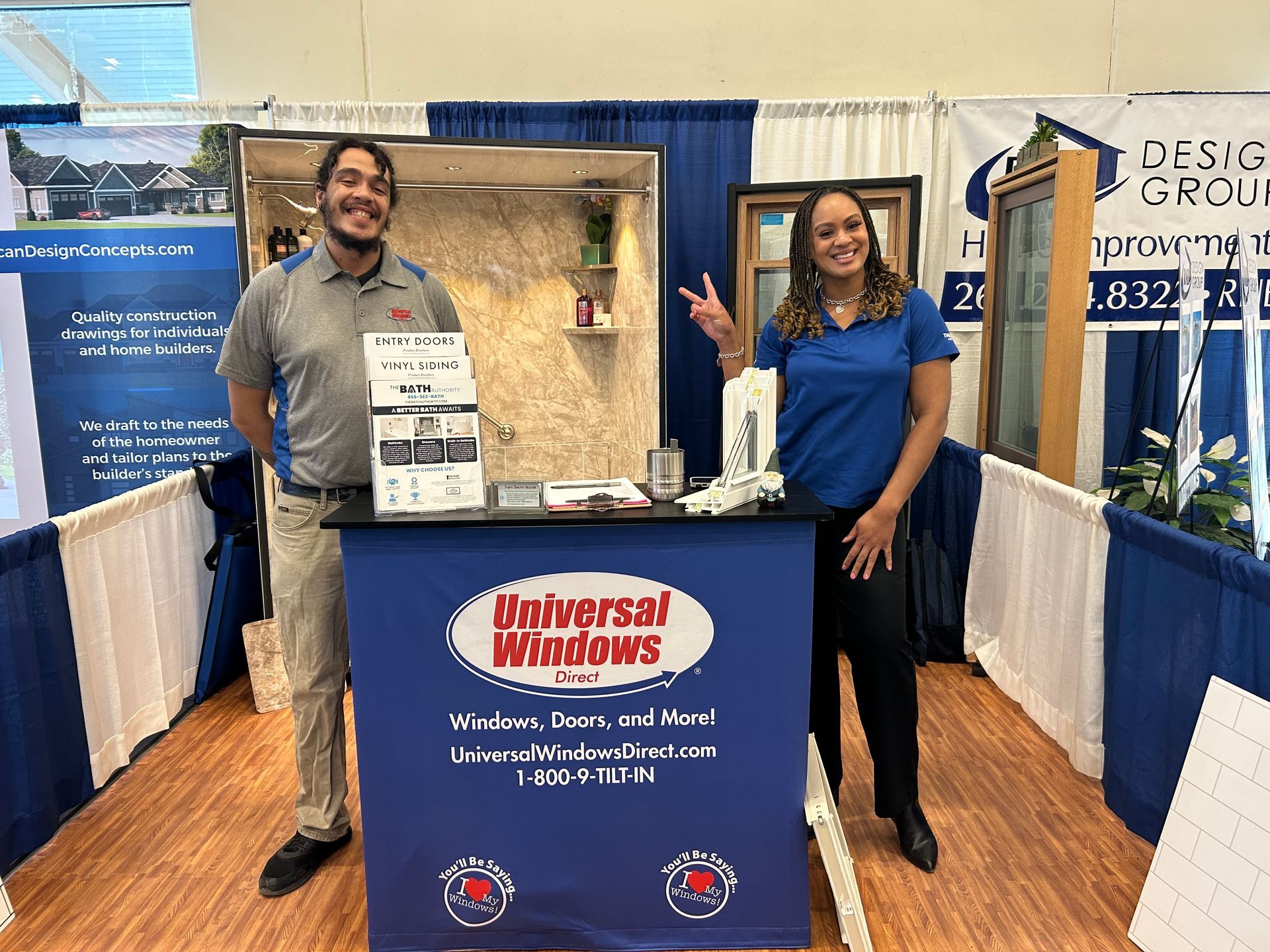 A man and a woman are standing in front of a table at a convention.