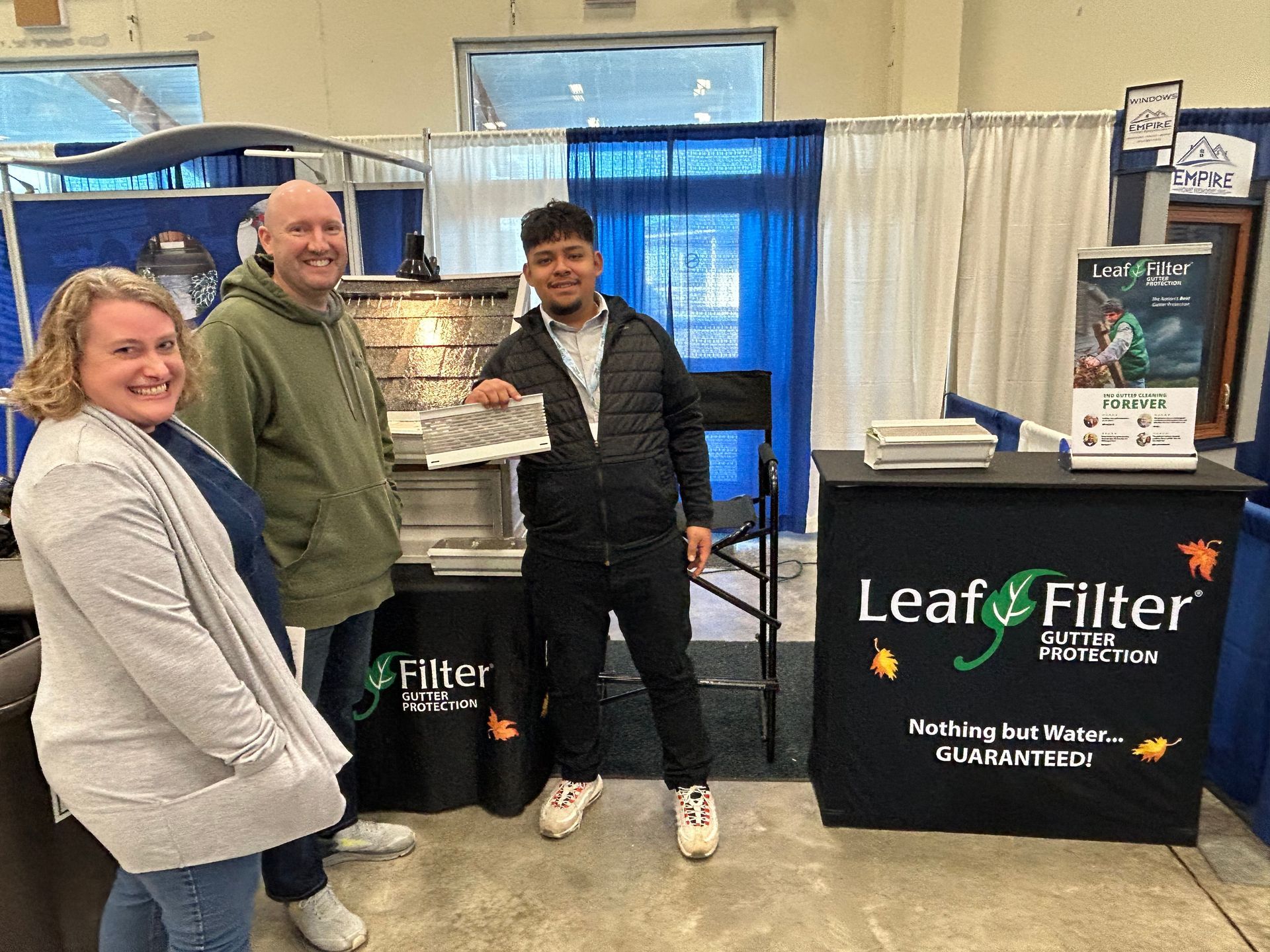 A man and two women are standing in front of a leaf filter booth.
