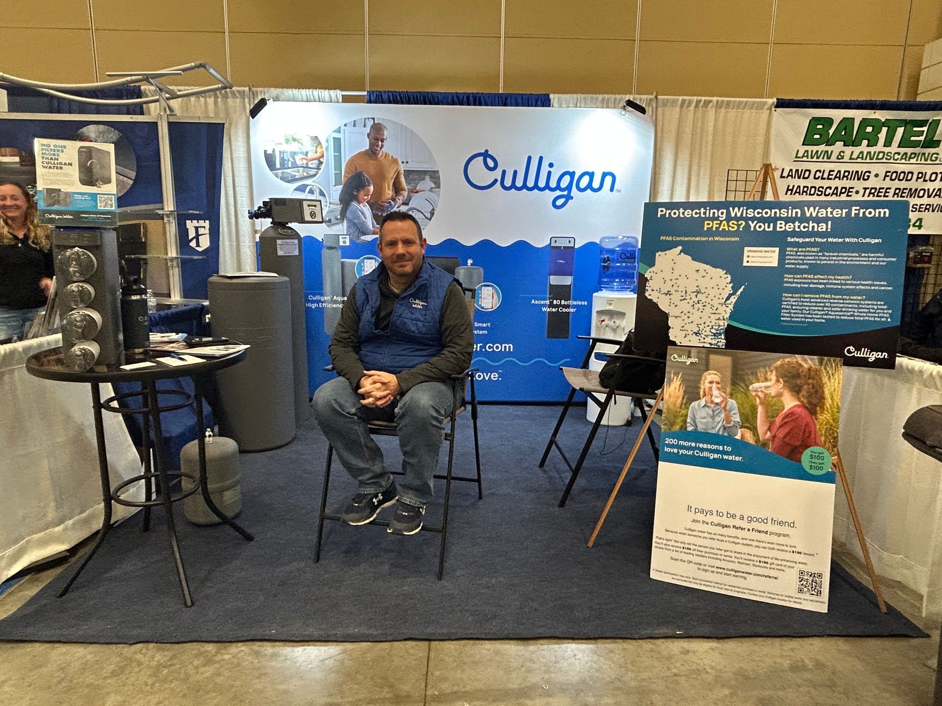 A man is sitting in a chair in front of a sign that says culligan.
