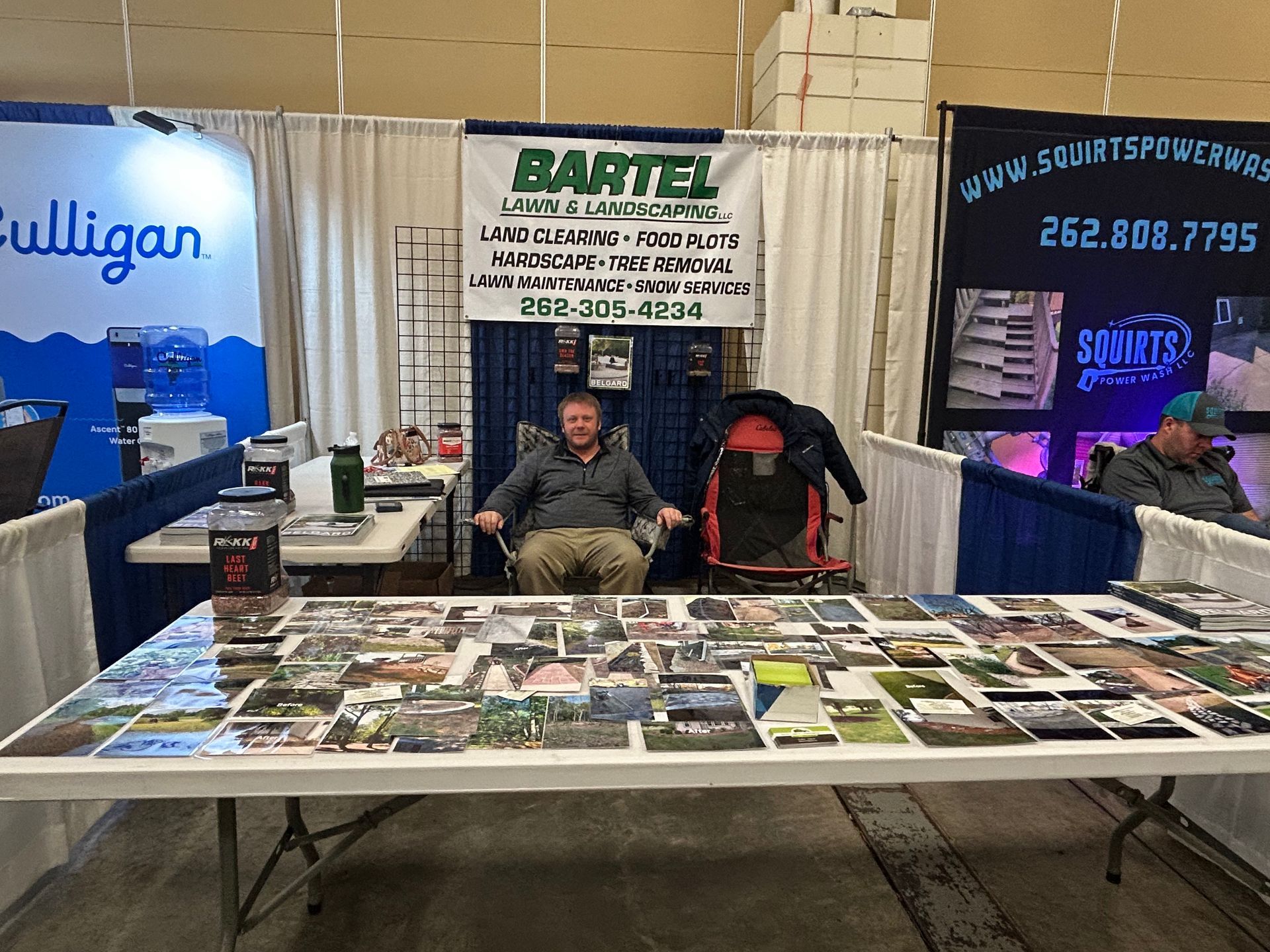 A man is sitting at a table with a sign that says bartel