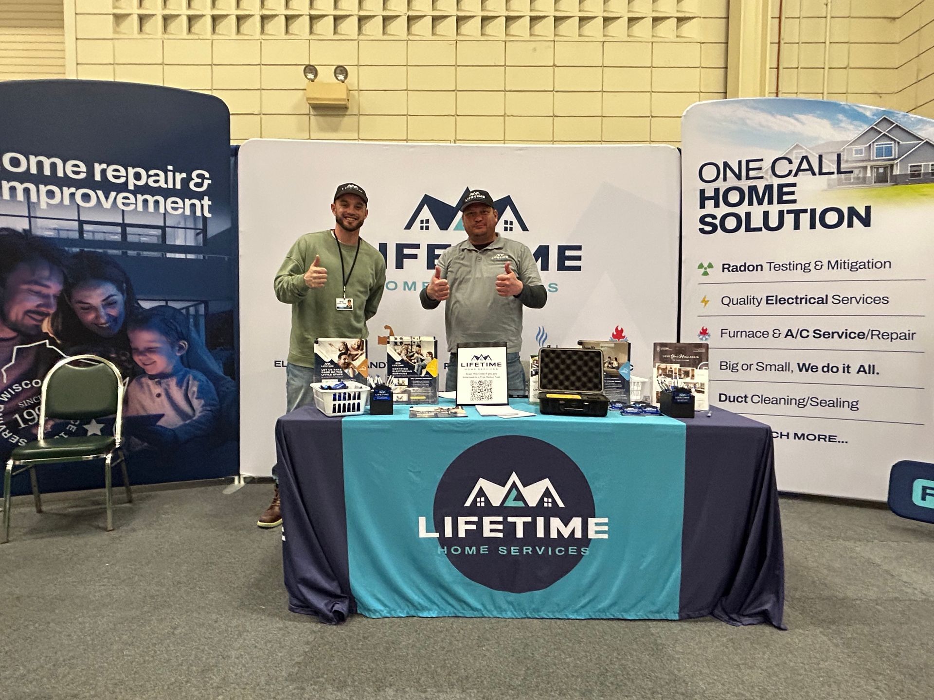 Two men are standing in front of a table with a lifetime sign on it.