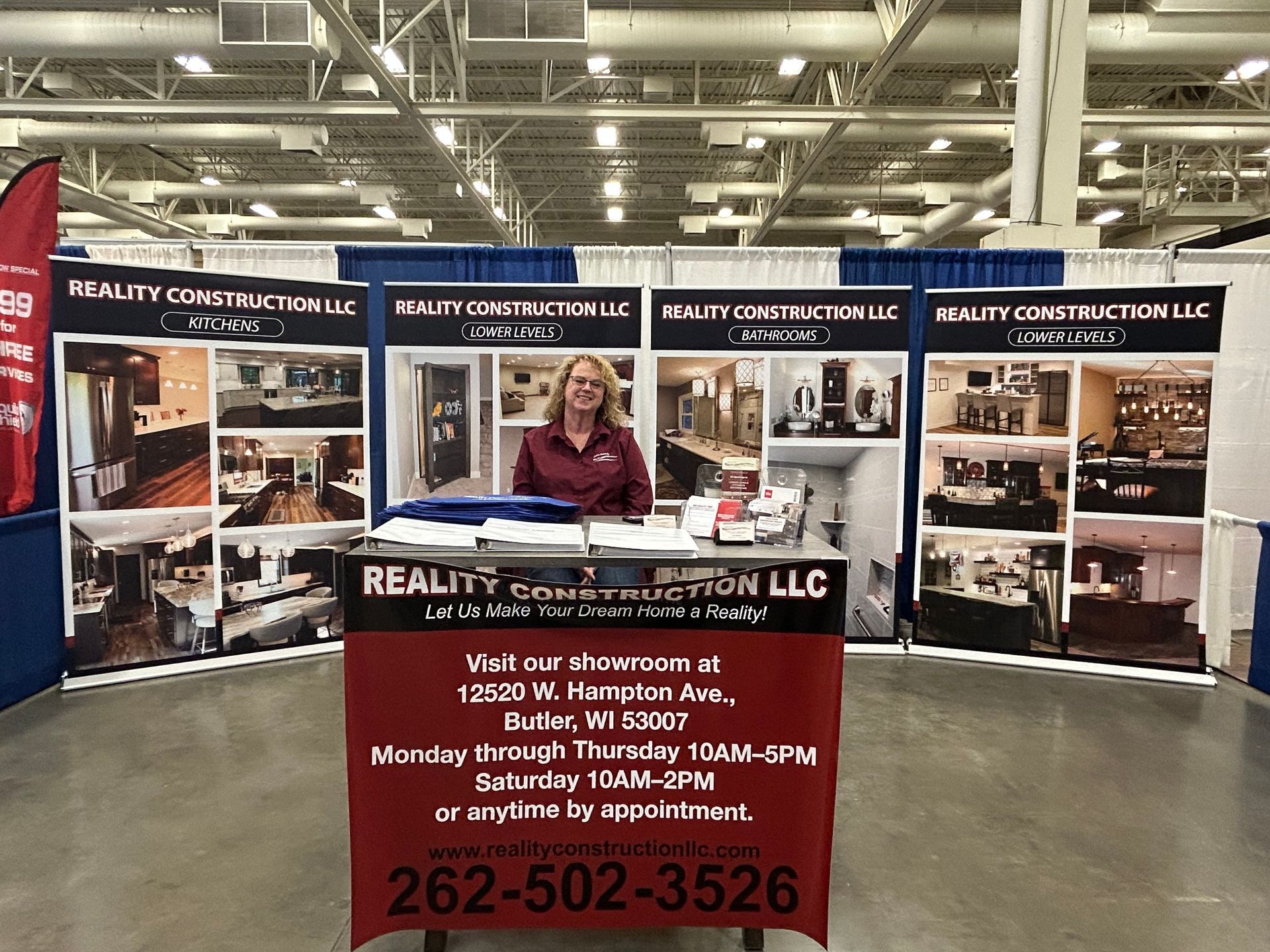 A woman is sitting at a booth at a convention.