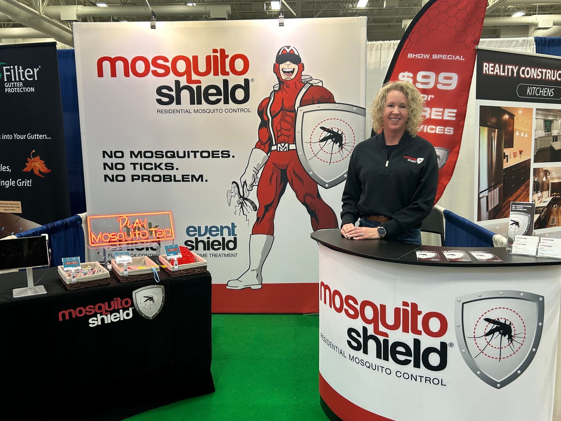 A woman is standing in front of a mosquito shield booth.