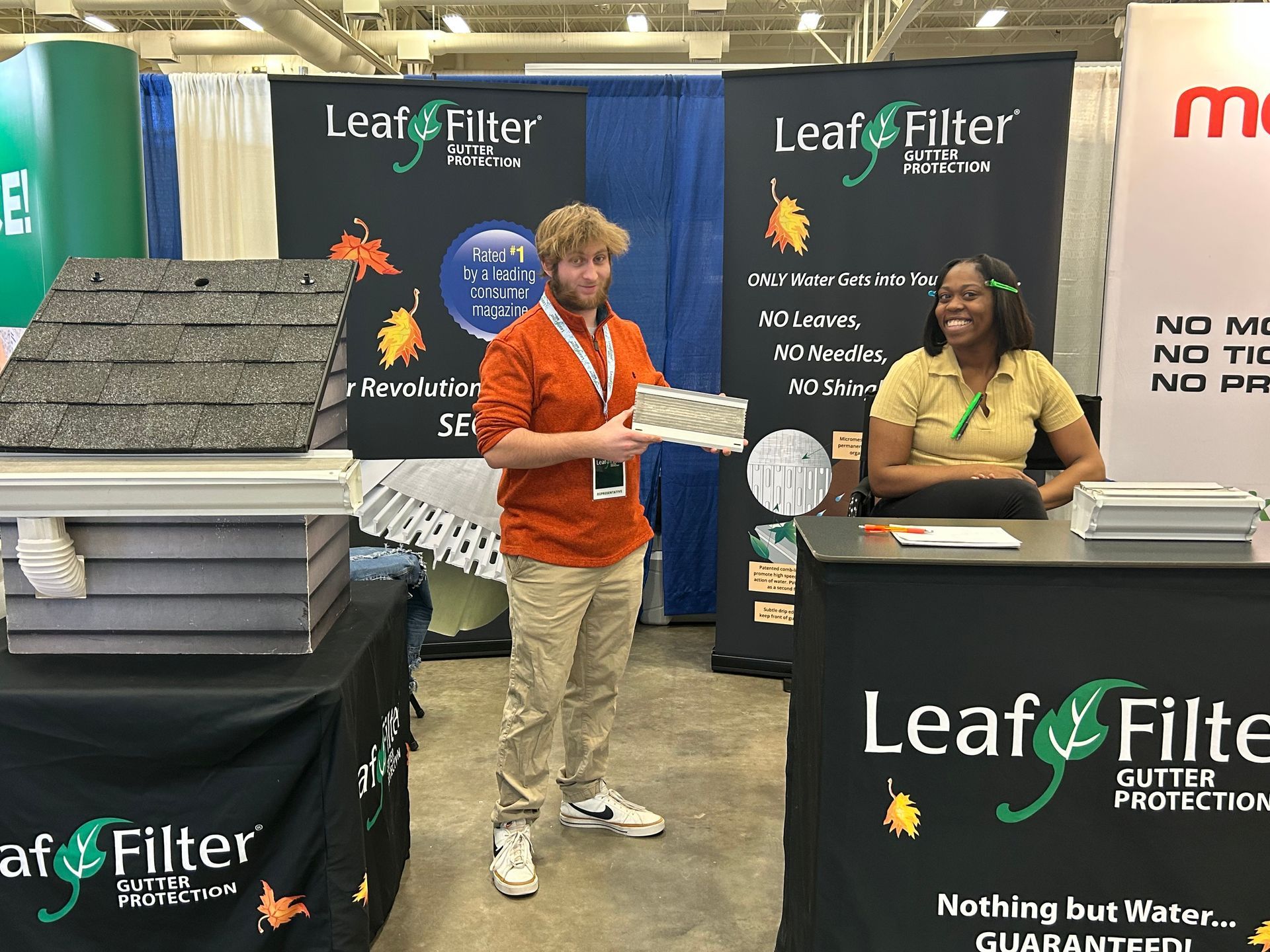 A man and a woman are standing in front of a leaf filter booth.