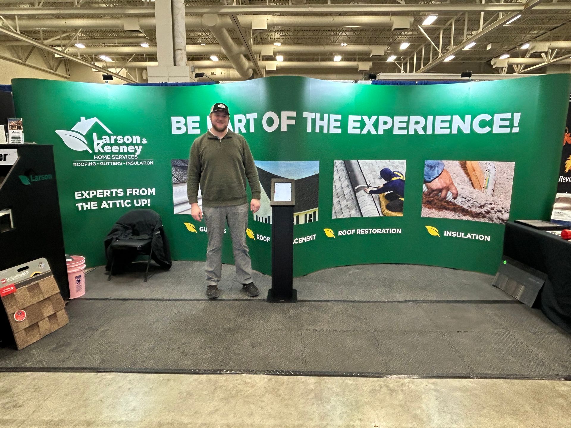 A man stands in front of a green wall that says be part of the experience