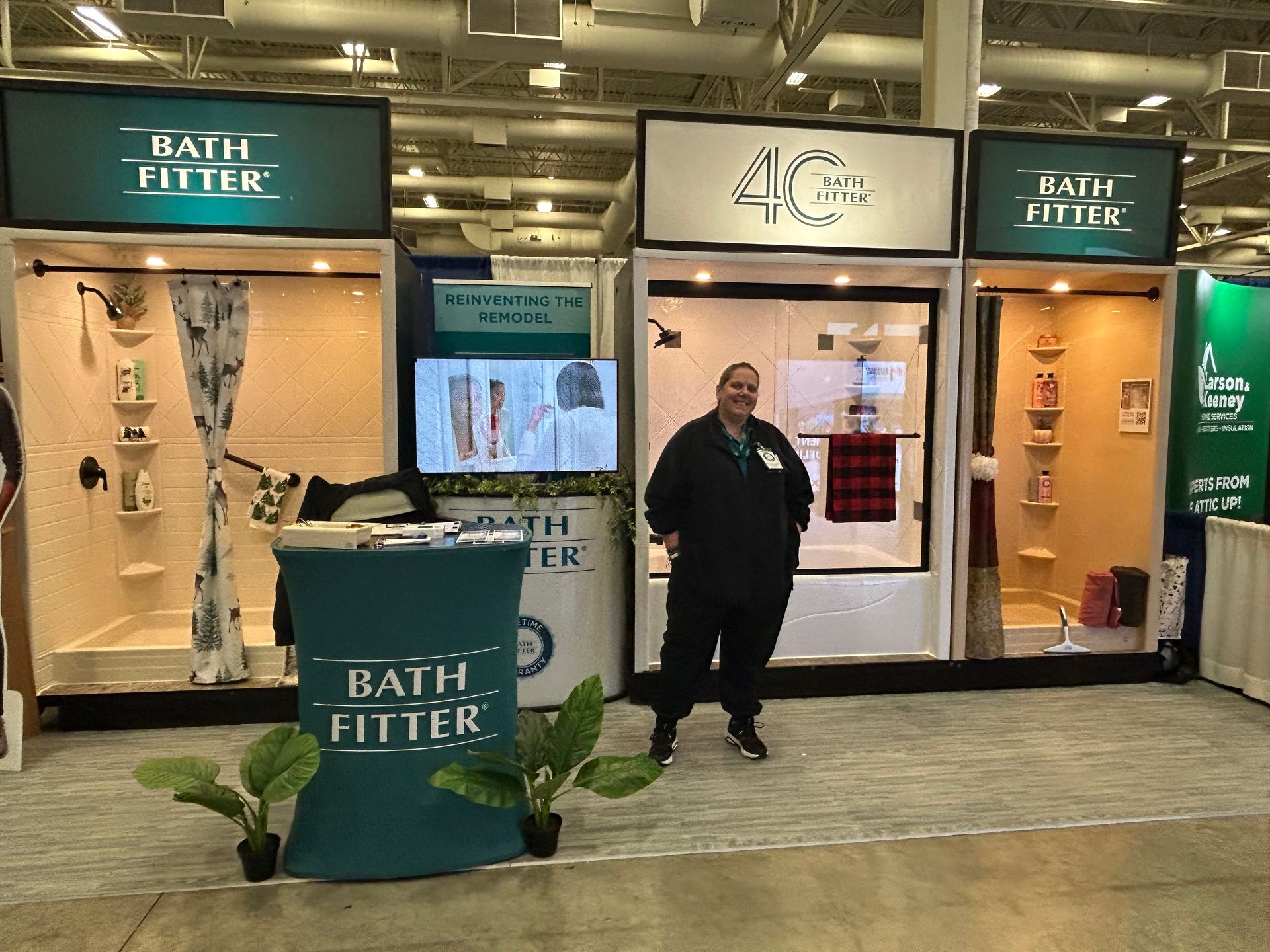 A man is standing in front of a bath fitter booth